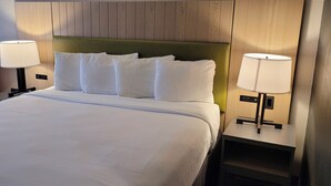 A hotel room with a large bed, two bedside lamps, and a red chair. - IHV-A Country Living (Canton)