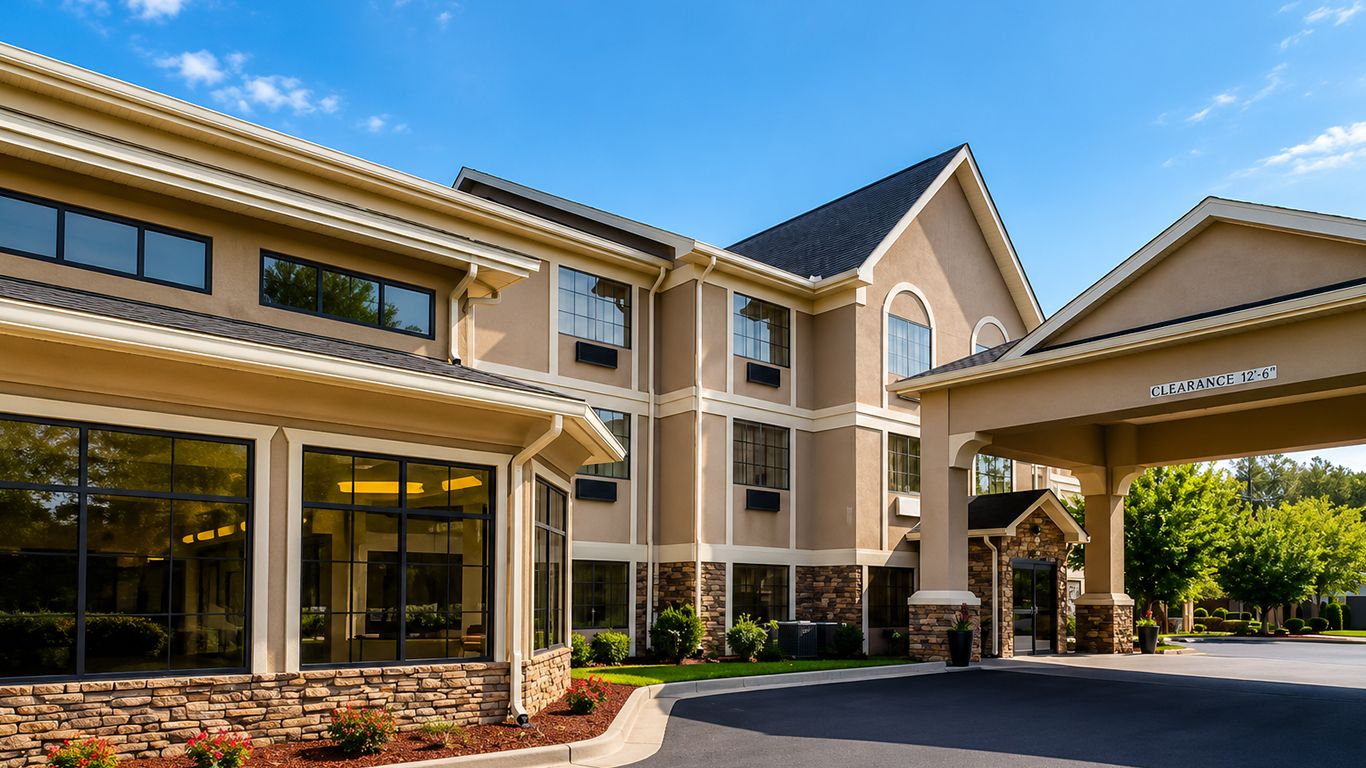 A multi-story building with a clear entrance, stone facade, and large windows.