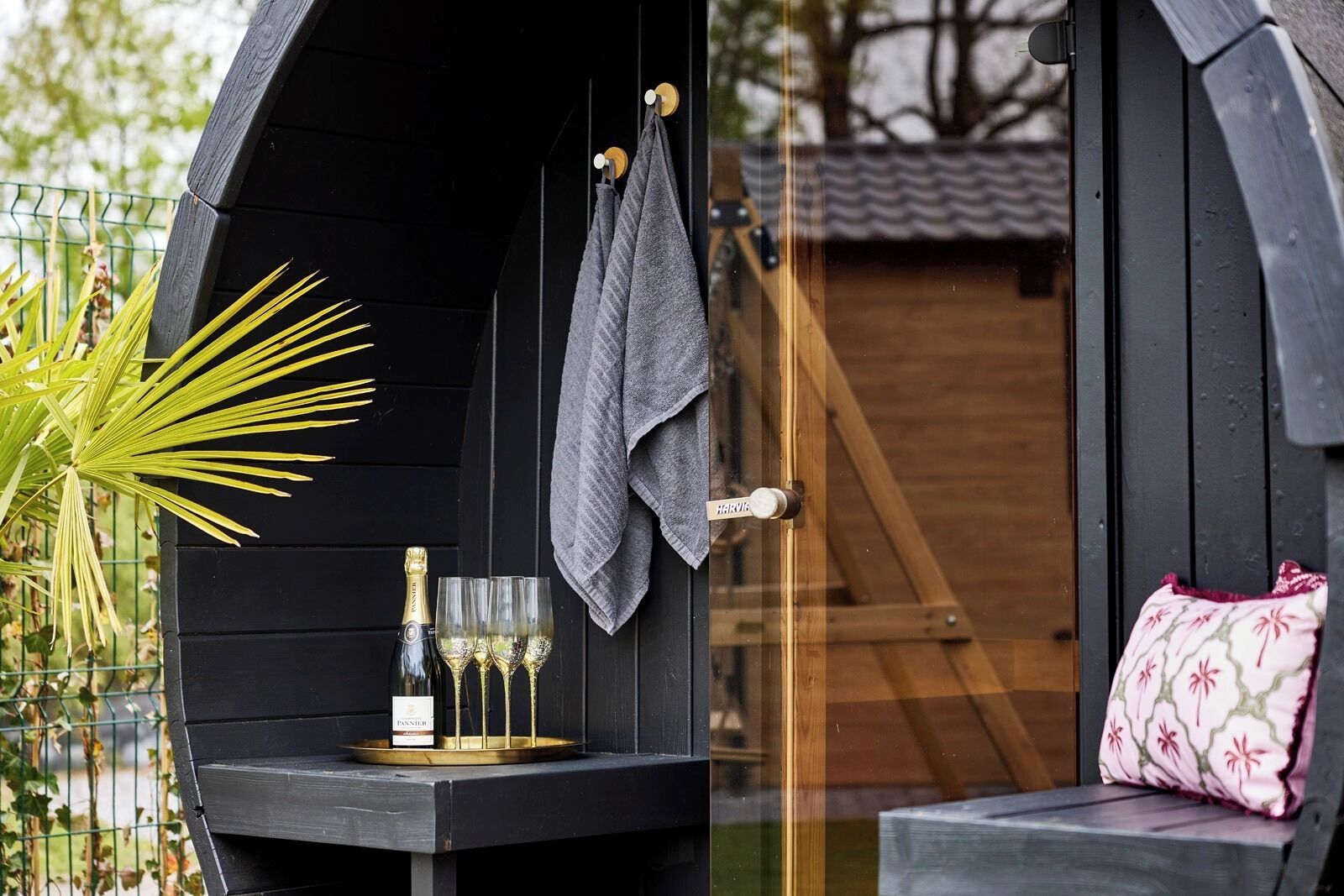 A cozy outdoor seating area with a black wooden structure, a bottle of champagne, and glasses on a tray.