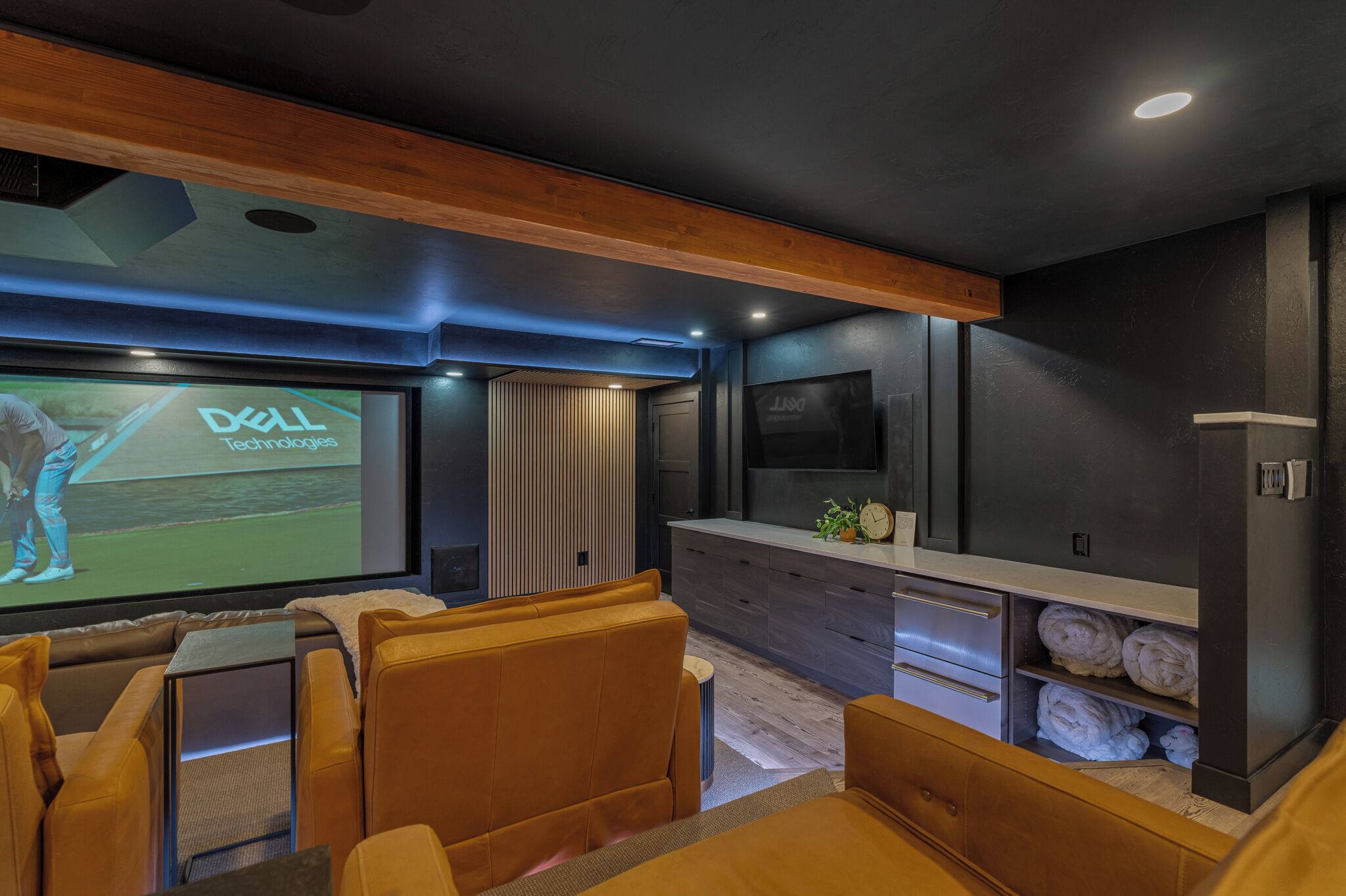 Un système de cinéma maison moderne, doté d’un grand écran, de sièges confortables et d’un plafond en bois.
