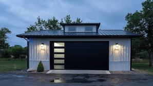 Ett garage med en svart dörr och två väggmonterade lampor.