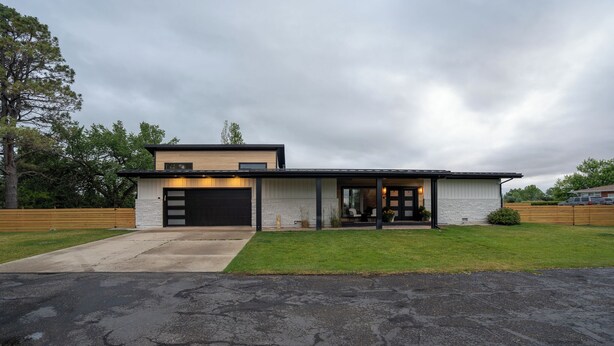 Ett modernt hus i två våningar med garage, en veranda och en välskött gräsmatta.