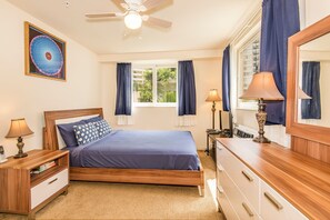 A bedroom with a bed, nightstands, a dresser, a ceiling fan, and a window with curtains. - The Cove Waikiki Condo W/full Kitchen by the Beach and Free Parking/wifi (Honolulu)