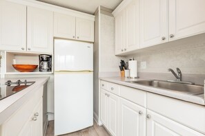 A kitchen with white cabinetry, a built-in coffee maker, a stainless steel sink, and a wooden countertop. - Mountain & Golf Course Views Family Island Colony Condo & Lots of Amenities (Honolulu)