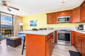 A modern kitchen with a central island, stainless steel appliances, and wooden cabinets. - Golf Course-city View Condo at the Waikiki Banyan By the Beach & Restaurants (Honolulu)