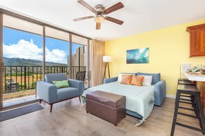 A bedroom with a large bed, a sofa, a ceiling fan, and a view of the outdoors. - Golf Course-city View Condo at the Waikiki Banyan By the Beach & Restaurants (Honolulu)