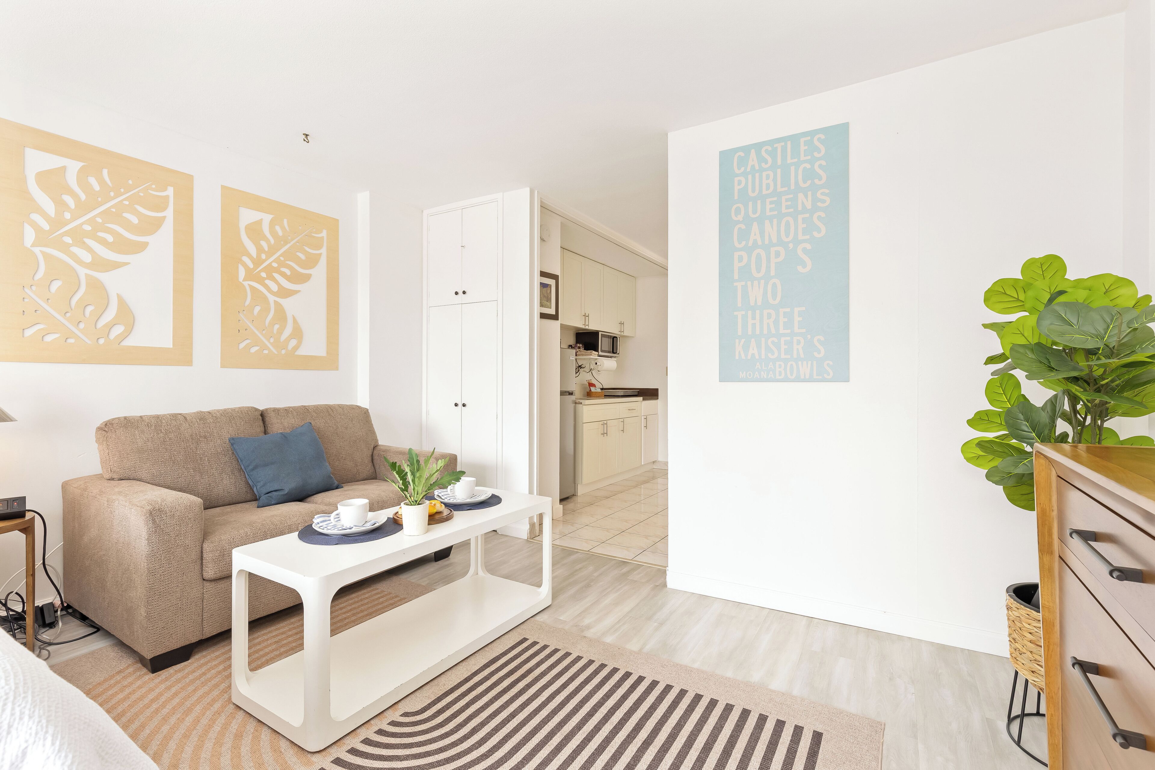 Uma sala de estar moderna com sofá, mesa de centro e arte decorativa com folhas.