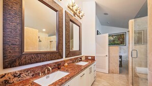 A modern bathroom with two sinks, large mirrors, and a shower area.