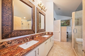 A modern bathroom with two sinks, large mirrors, and a shower area.