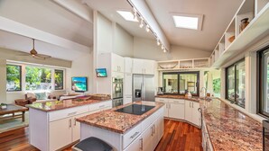 A modern kitchen with white cabinetry, granite countertops, and a central island.