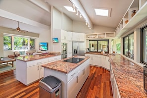 A modern kitchen with white cabinetry, granite countertops, and a central island.
