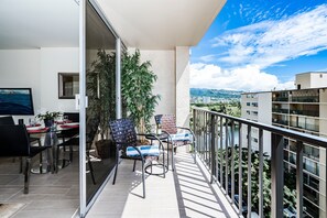 A balcony with a dining setup, including chairs, a table, and a potted plant. - Fairway Villa in the Heart of Waikiki by the Beach W/rooftop Pool & Amenities (Honolulu)