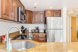 A modern kitchen with wooden cabinets, stainless steel appliances, granite countertops, and a built-in oven. - Ocean-lagoon & Fireworks Views at the Ilikai Hotel W/spectacular Amenities (Honolulu)