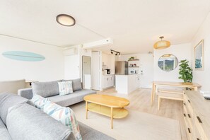 A modern living room with a sofa, coffee table, and dining area. - Golf Course & MT Renovated Condo at Island Colony & Spectacular Amenities (Honolulu)