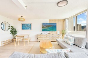 A modern living room with a sofa, a dining table, and a TV. - Golf Course & MT Renovated Condo at Island Colony & Spectacular Amenities (Honolulu)