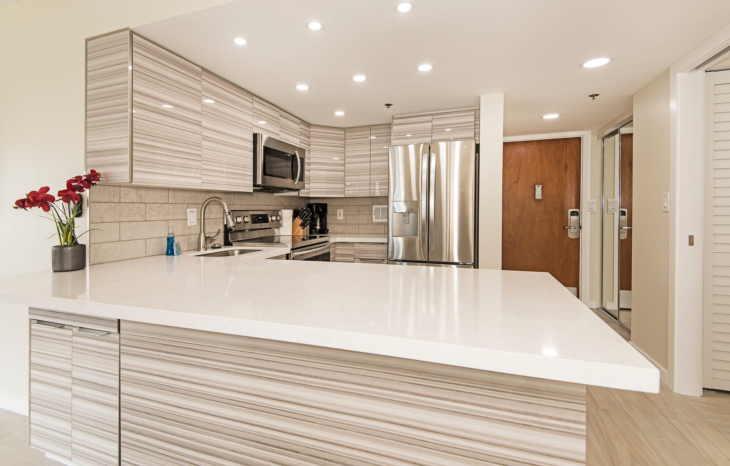 Una cocina moderna con una isla grande, electrodomésticos de acero inoxidable y una puerta de madera.
