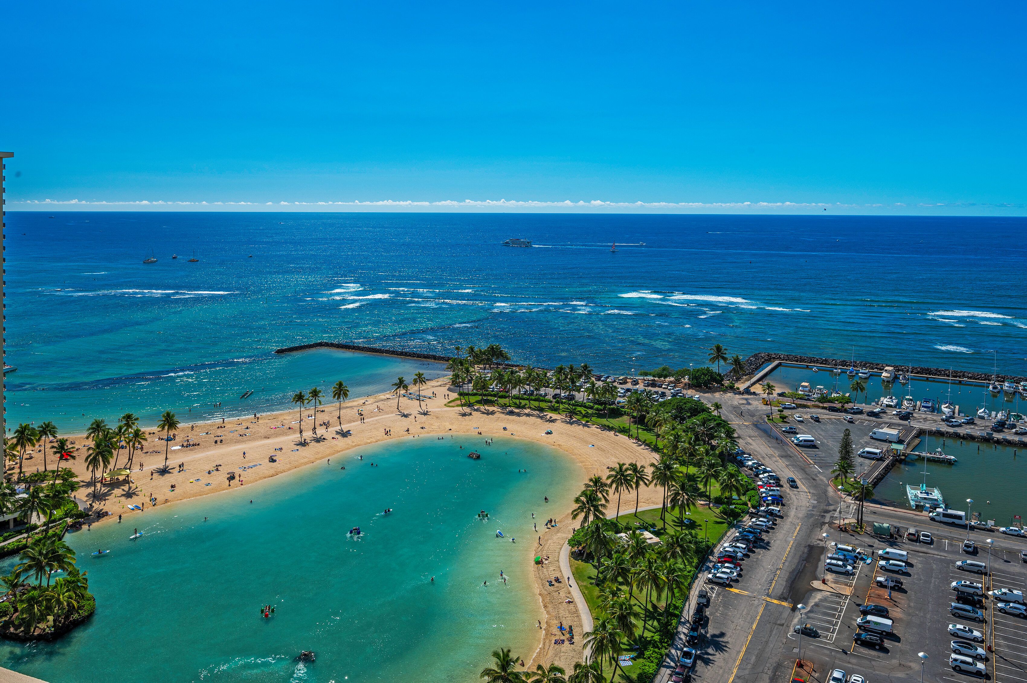 A coastal area with a beach, a parking lot, and a marina.