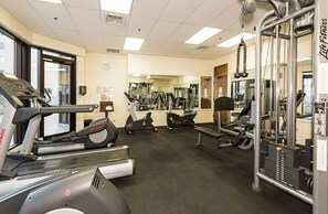 Ein Fitnessstudio mit Laufbändern, Crosstrainern und Gewichten.