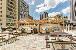 Eine Außenpatio-Terrasse mit mehreren Grillanlagen und Picknicktischen.
