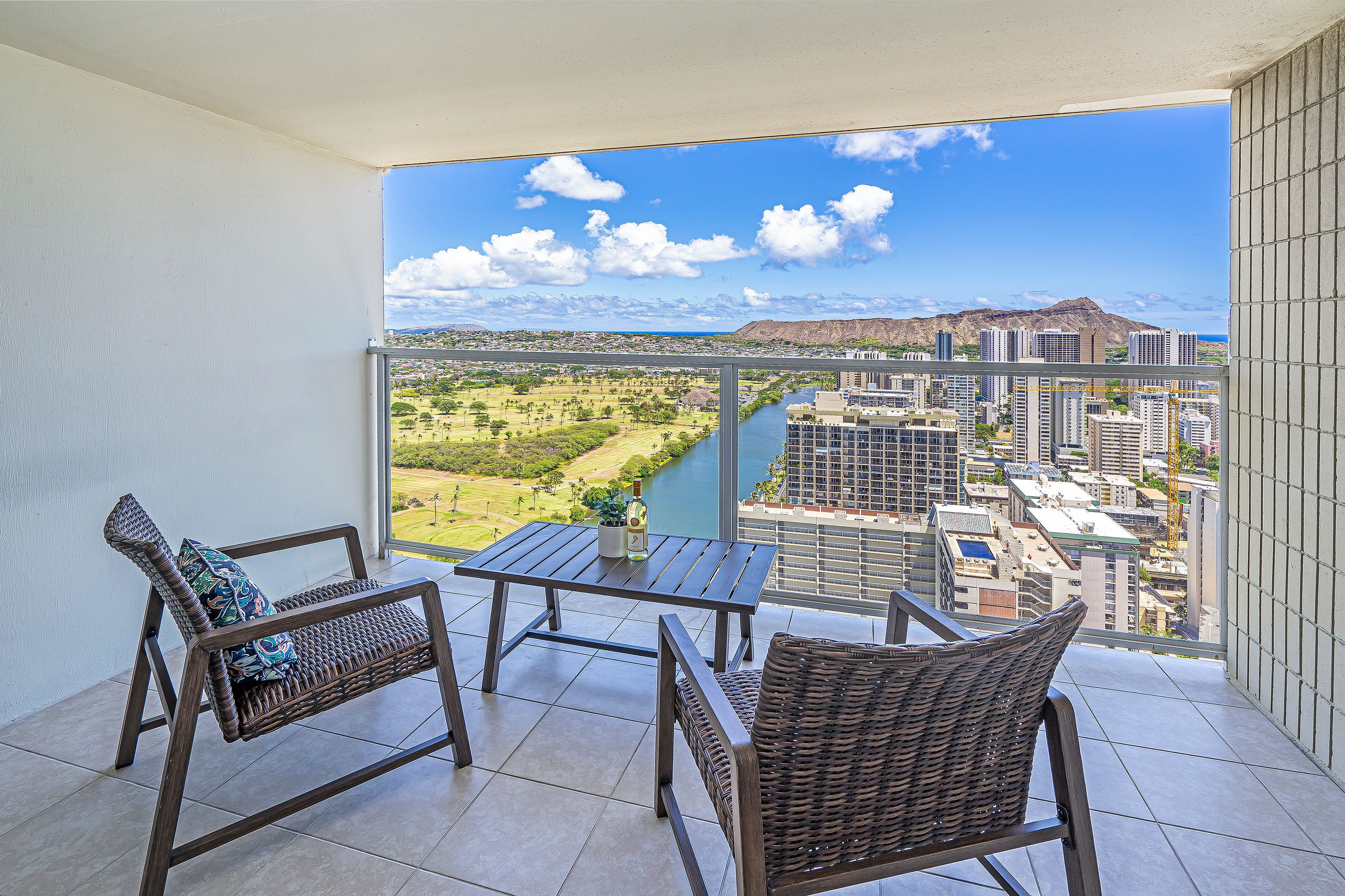 Un balcón con mobiliario de mimbre, una mesa y vistas a la ciudad y al río.