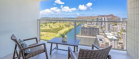 Un balcón con mobiliario de mimbre, una mesa y vistas a la ciudad y al río.