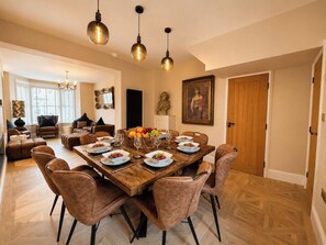 A dining area with a wooden table set for six, surrounded by six brown leather chairs. - Number 8 (Llandudno)