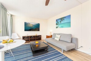 A living room with a sofa, coffee table, and a painting of a beach scene. - Ocean-diamond Head Views Condo at Pacific Monarch Hotel Steps to the Beach (Honolulu)