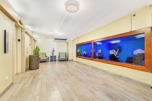 A hotel lobby with a reception desk, seating area, and a large aquarium. - Ocean-diamond Head Views Condo at Pacific Monarch Hotel Steps to the Beach (Honolulu)