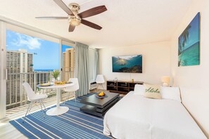 A hotel room with a balcony, a bed, a desk, and a TV. - Ocean-diamond Head Views Condo at Pacific Monarch Hotel Steps to the Beach (Honolulu)