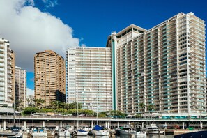 Ein Hochhaus-Hotel mit mehreren Balkonen, eine Marina mit Booten und einem strahlend blauen Himmel.