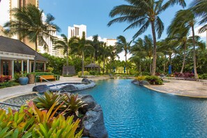 A resort pool with palm trees, a gazebo, and a building with a sloped roof. - Luxurious Ocean View Panoramic PH at The Watermark W/spectacular Amenities (Honolulu)