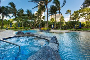A swimming pool with a hot tub, surrounded by palm trees and a building in the background. - Luxurious Ocean View Panoramic PH at The Watermark W/spectacular Amenities (Honolulu)