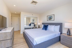 Ein modernes Hotelzimmer mit einem großen Bett, Nachttischen, einem Kleiderschrank und einem Spiegel.