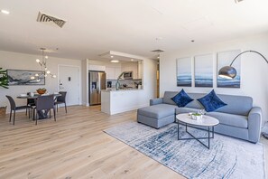 Ein modernes Wohnzimmer mit grauem Sofa, einem Couchtisch und einem Essbereich mit Tisch und Stühlen.