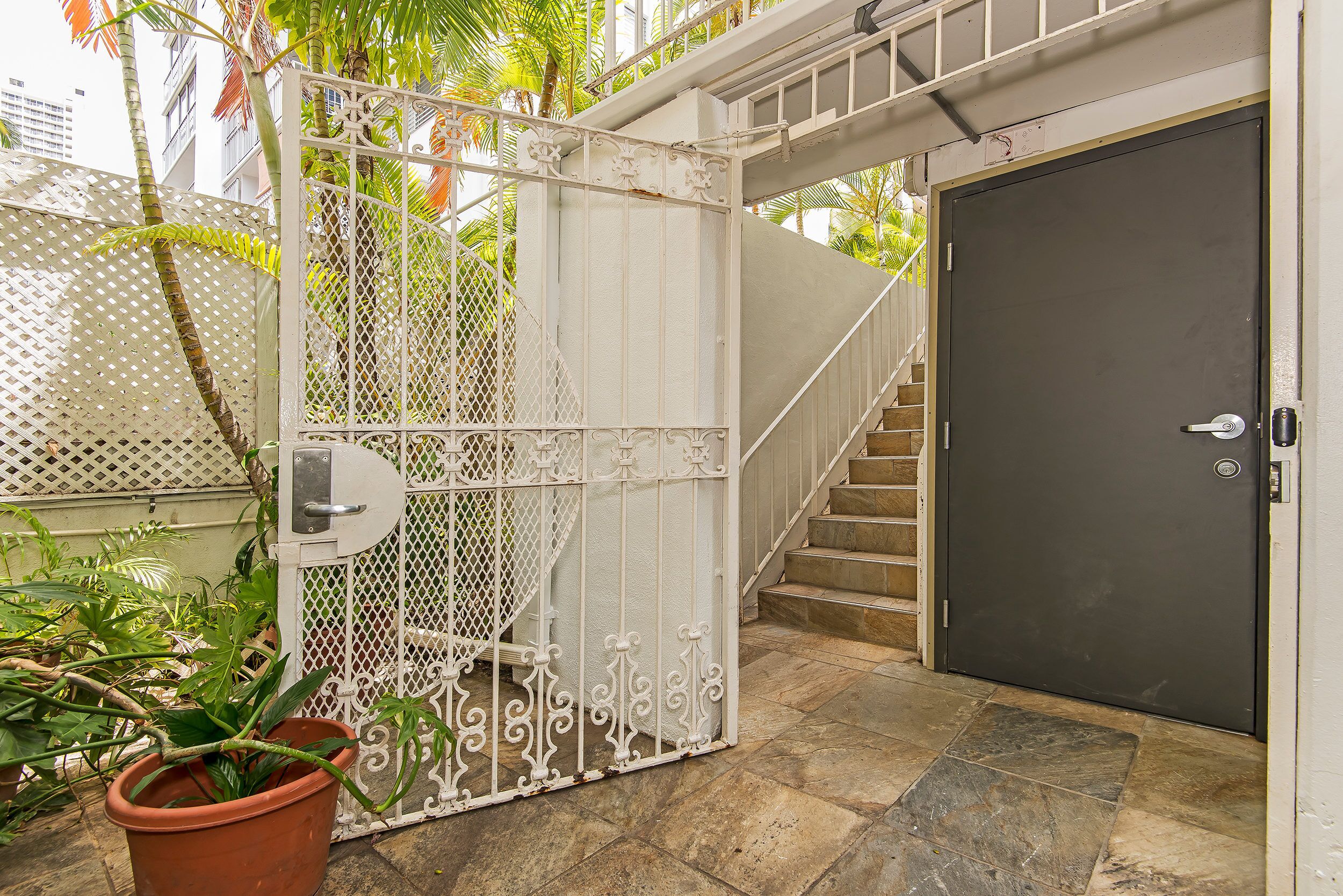 A gated entrance with a metal gate, a dark door, and a staircase leading to an upper level.