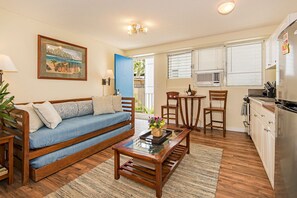 A living room with a sofa, coffee table, and a painting on the wall. - Family Vacation Condo W/full Kitchen by the Beach & Near Shops & Restaurants (Honolulu)