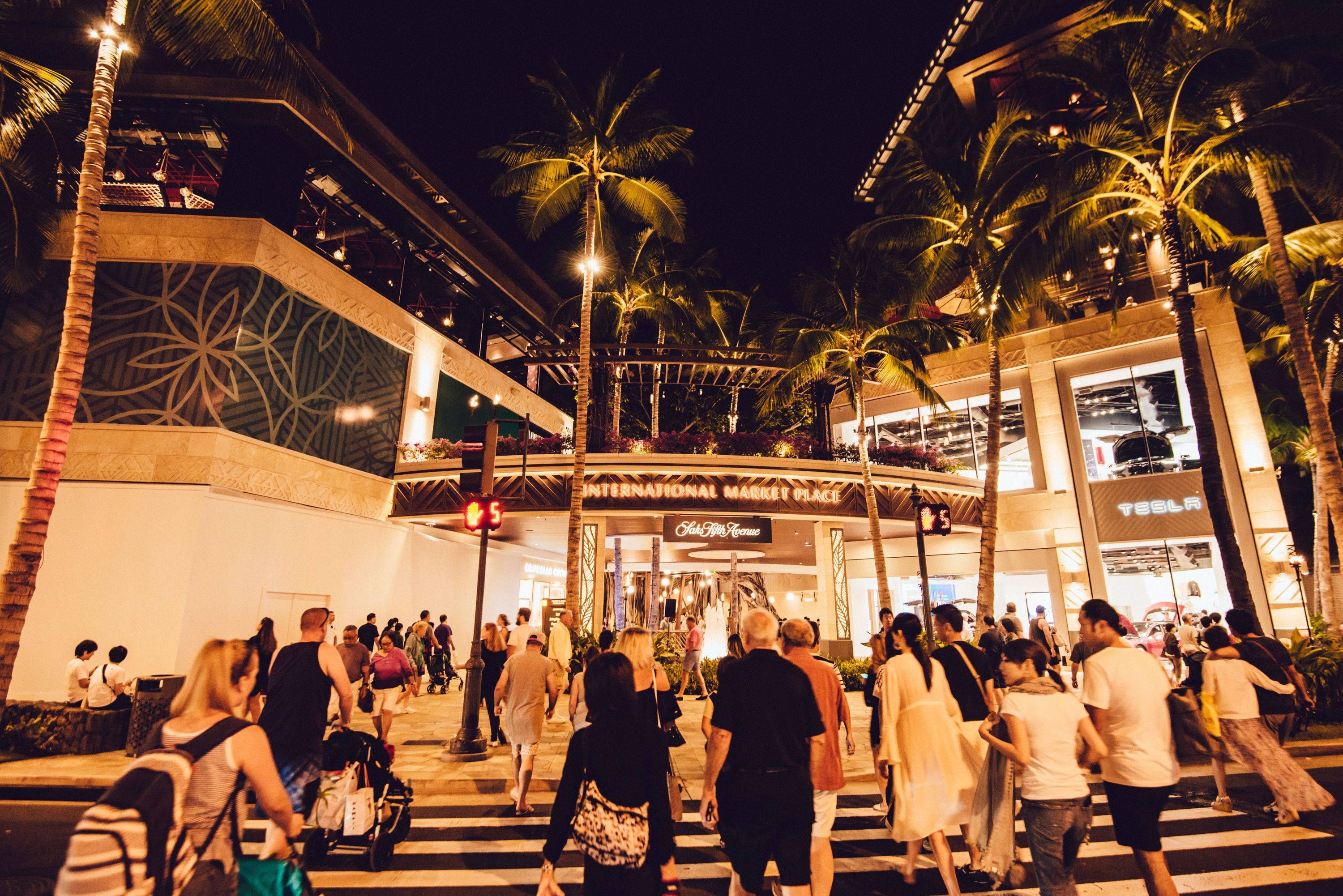 Una concurrida zona peatonal con palmeras y un edificio que dice 'International Market Place'.