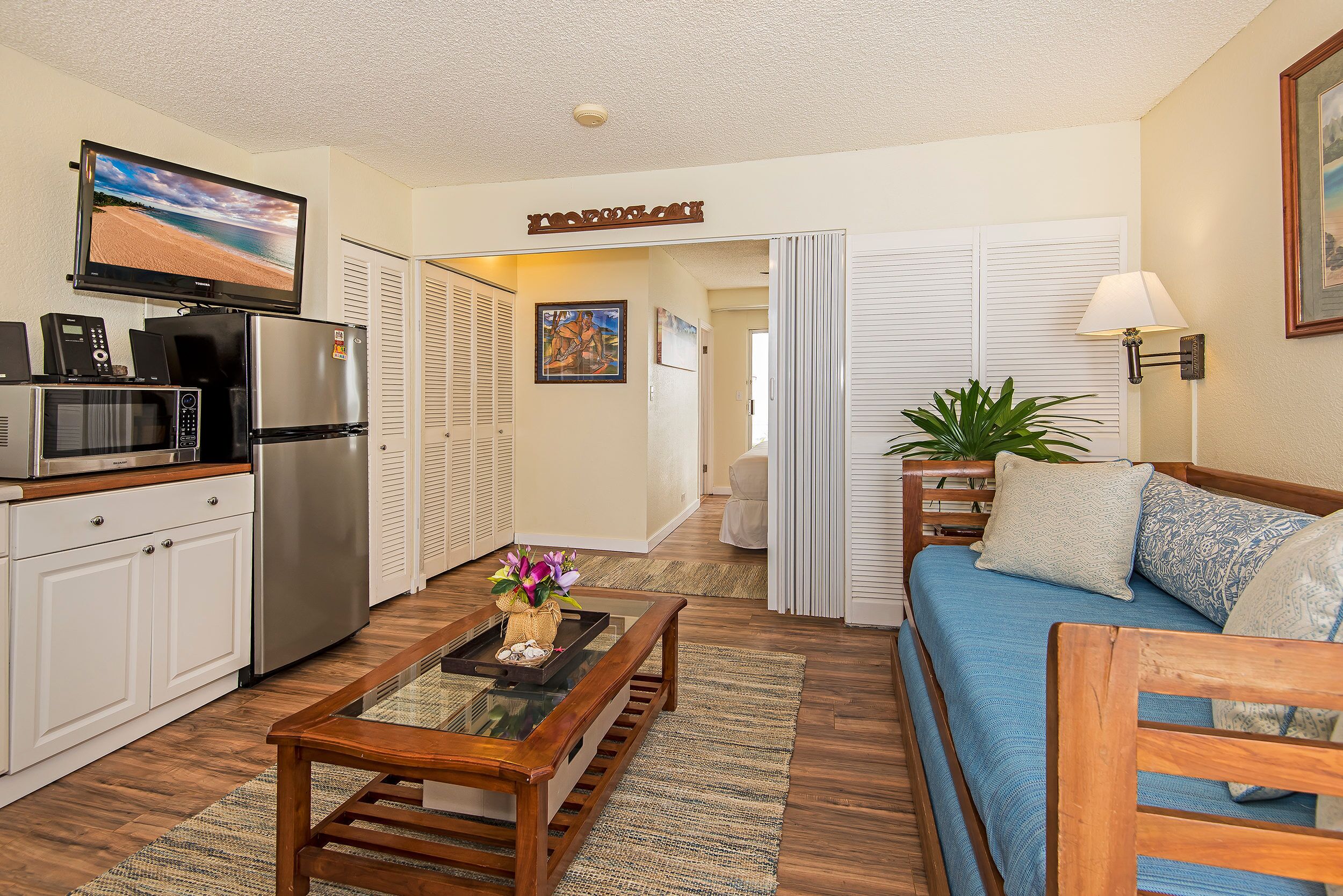 A compact living space with a kitchenette, a flat-screen TV, a sofa, and a dining table.