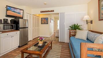 A compact living space with a kitchenette, a flat-screen TV, a sofa, and a dining table.