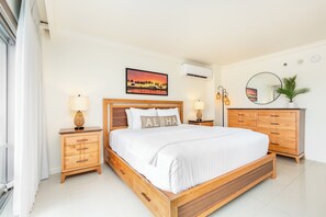 Ein Schlafzimmer mit einem hölzernen Bett, Nachttischen, einem Spiegel und einer Wandklimaanlage.