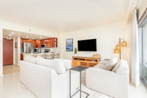 A modern living room with a sofa, a coffee table, and a flat-screen TV mounted on the wall. - Ocean & Fireworks Renovated Condo at Ilikai Hotel With Full Kitchen & Wifi (Honolulu)