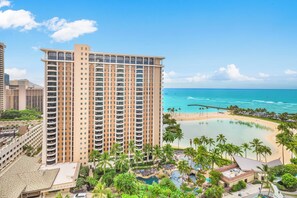 Ein hoch aufragendes Hotel mit mehreren Balkonen, einem Poolbereich am Strand und Blick auf den Ozean.