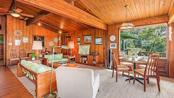 A cozy cabin interior with wooden walls, a dining area, and a sofa.