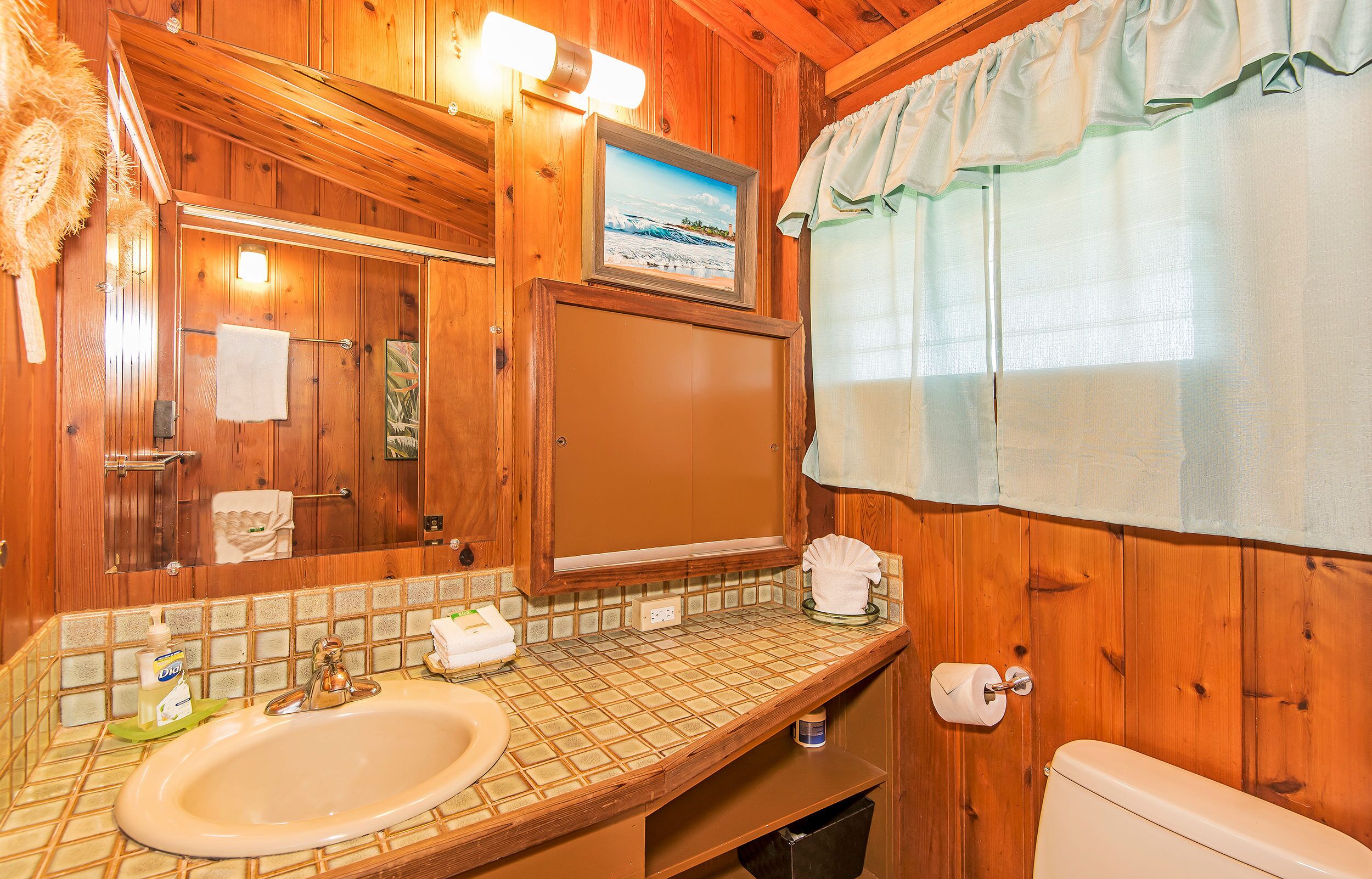 A wooden bathroom with a sink, mirror, and toilet.