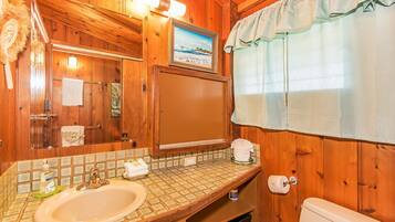 A wooden bathroom with a sink, mirror, and toilet.