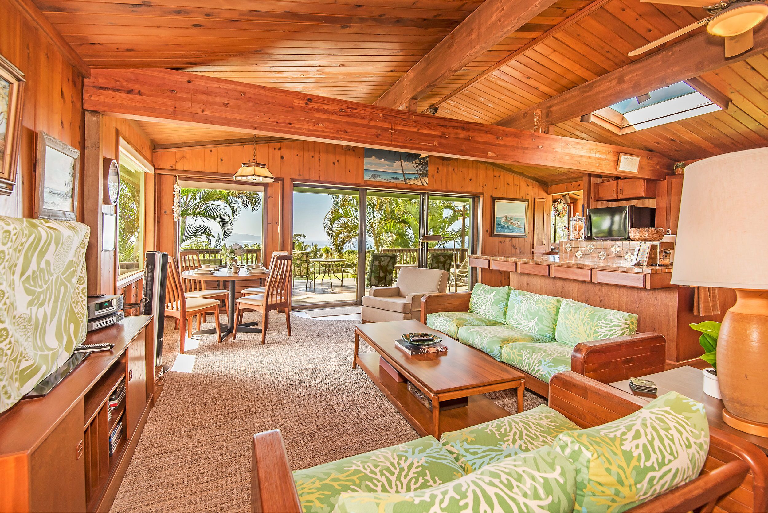 L’intérieur chaleureux d’un chalet avec des murs et un plafond en bois, un canapé, une table basse et un coin repas comprenant des chaises et une table.