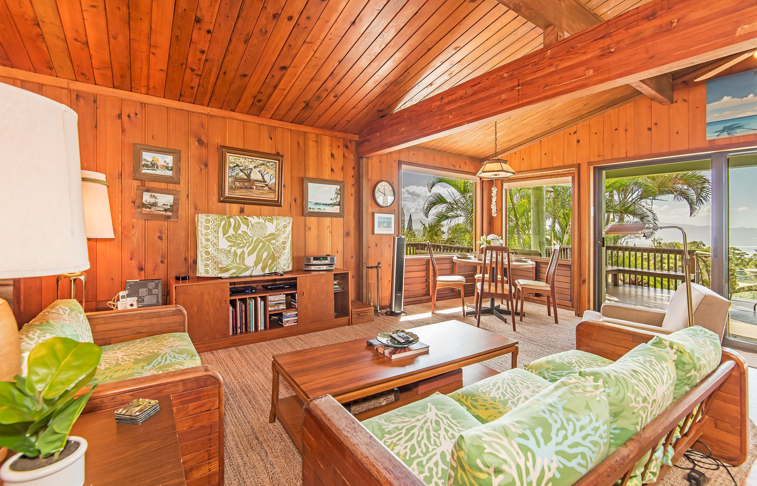 A wooden cabin interior with a living room, dining area, and a balcony with a view.