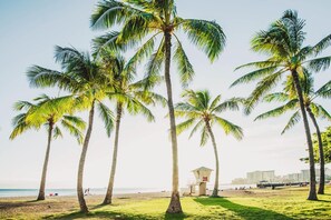 A beach with palm trees, a lifeguard tower, and a clear view of the ocean. - Steps From the Beach Family Retreat W/free Parking in Boutique Style Building (Honolulu)