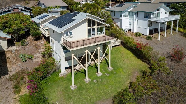 A two-story house with a balcony, solar panels, and a garden.