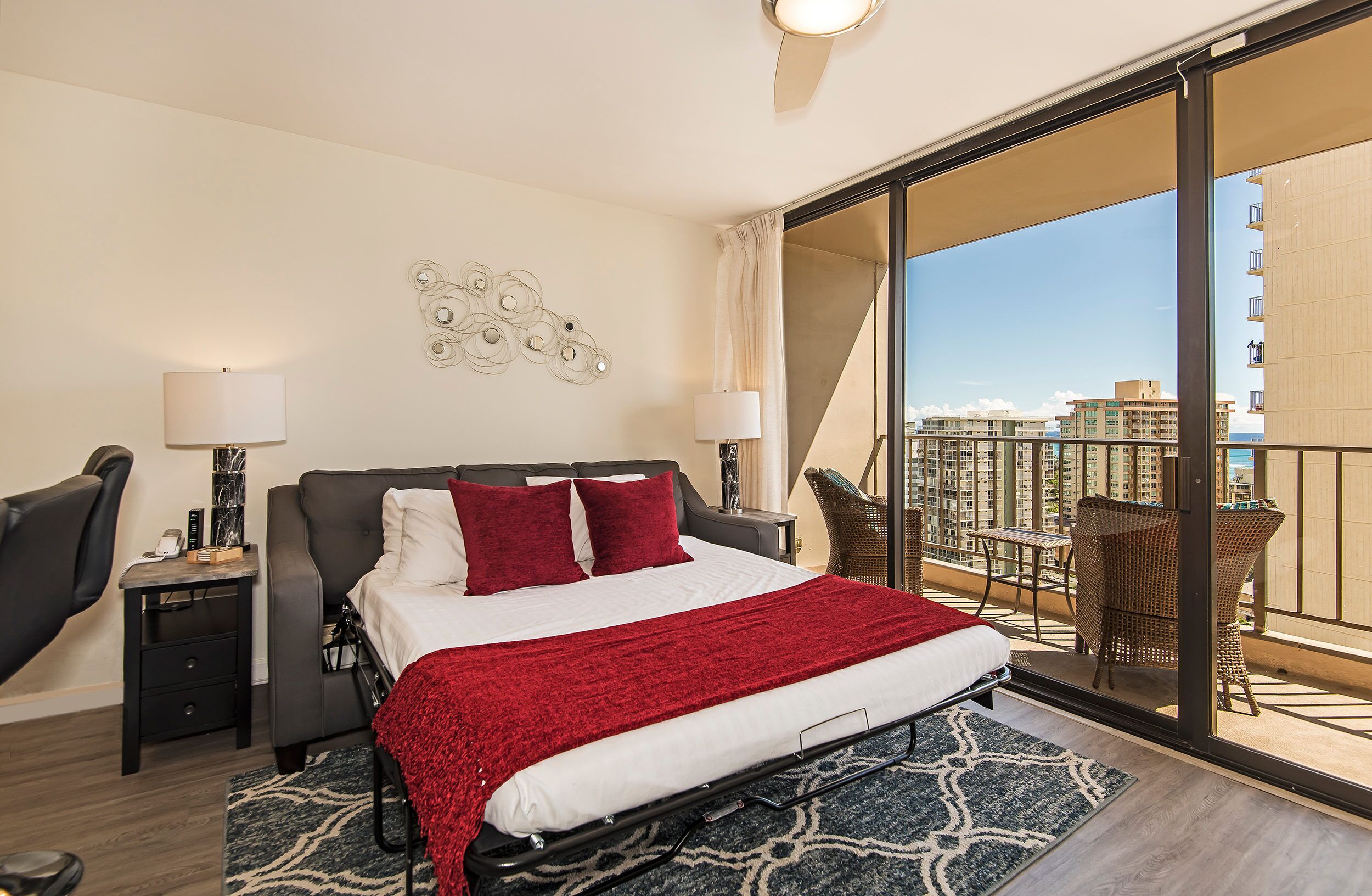 Una habitación de hotel con cama, escritorio, silla y balcón con vistas a edificios.